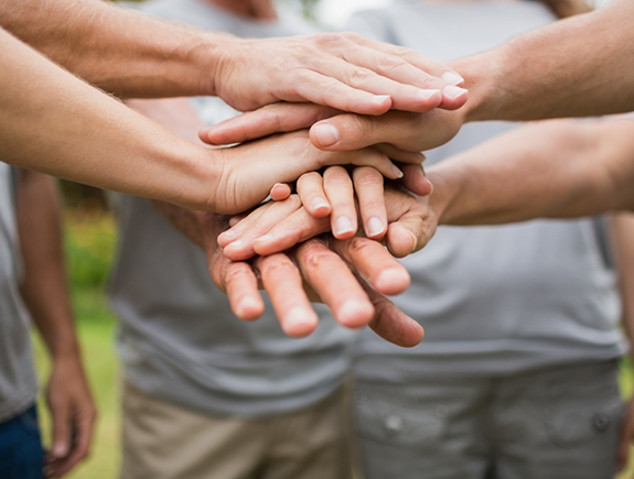 Group of people standing in the circle and placing their hands in the middle