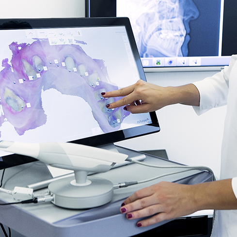 Dentist touching a screen that shows a model of a row of a patients teeth
