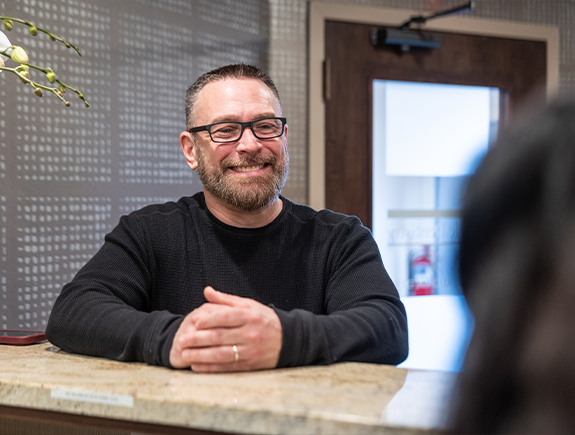 Smiling man checking in at the front desk of a dental office in Port Chester