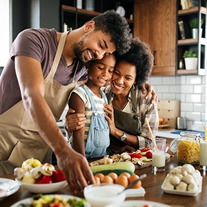 Man and woman cooking healthy meal with little girl in the kitchen