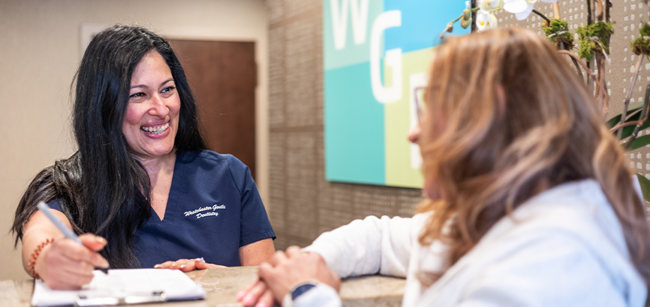 Dental team member at front desk helping a woman check in