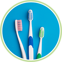 Three toothbrushes laying on a flat blue surface