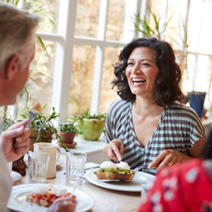 Woman smiling while eating with friends in restaurant