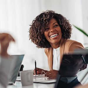 Woman smiling while taking notes during meeting