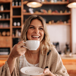 Woman smiling while enjoying coffee at restaurant