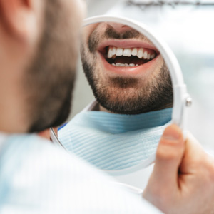 Patient smiling at reflection in handheld mirror