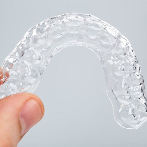 Close up of patient carefully holding their Invisalign tray