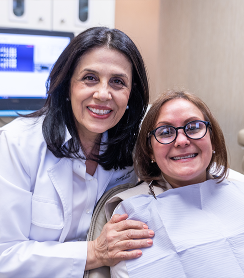 Doctor Alidadi smiling next to a woman in the dental chair