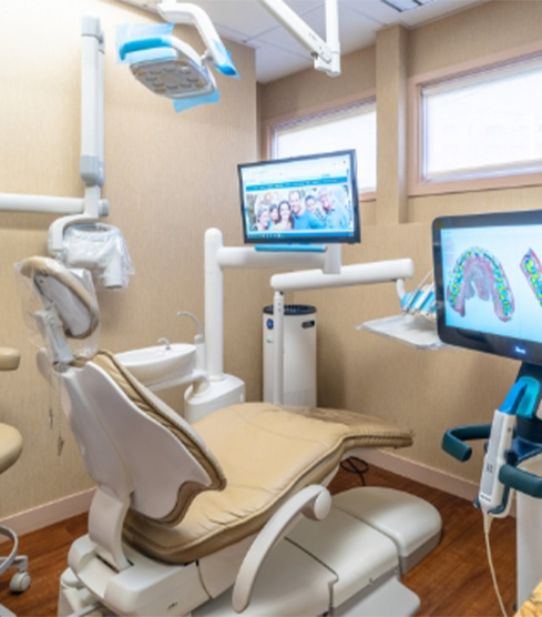 Doctor Alidadi smiling next to a woman in the dental chair