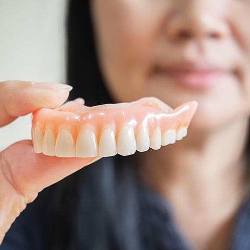 Dental professional holding a full denture