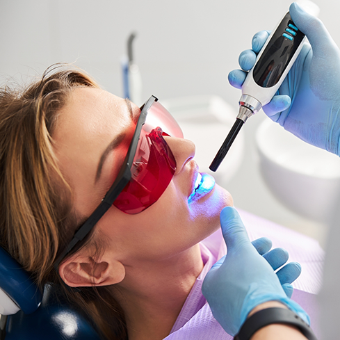 Dental patient having an ultraviolet light shone onto her teeth
