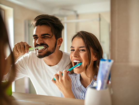 Man and woman brushing their teeth together