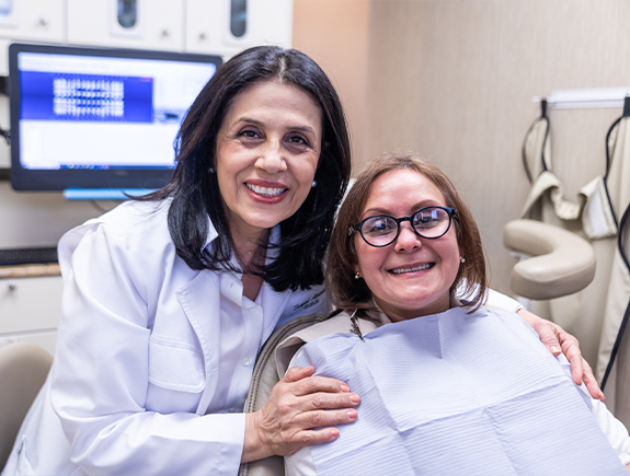 Dentist smiling next to a woman in the dental chair