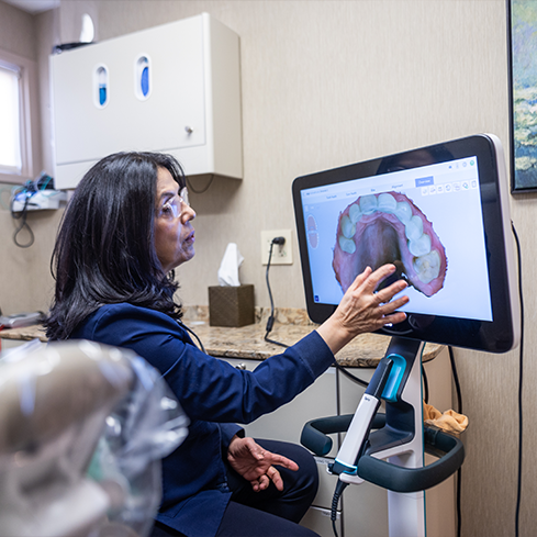 Dentist touching a monitor that shows a digital impression of a row of teeth