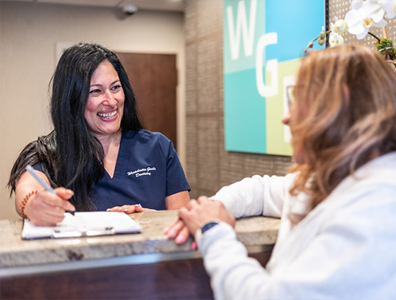 Dental office receptionist telling a patient about their in house dental membership plan in Port Chester