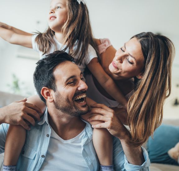 Mother father and small daughter laughing together in their living room