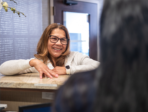 Woman smiling while checking in at the front desk of a dental office