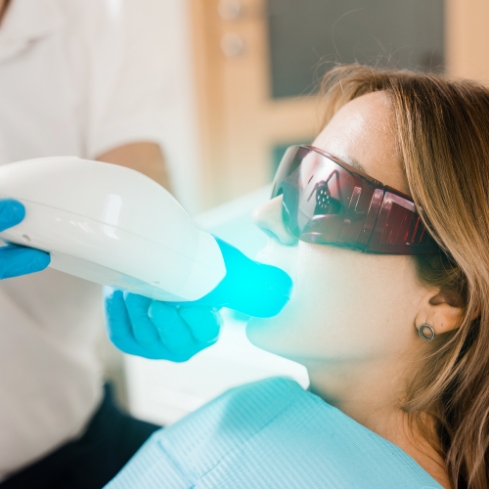 Male dentist speaking to female patient in treatment chair