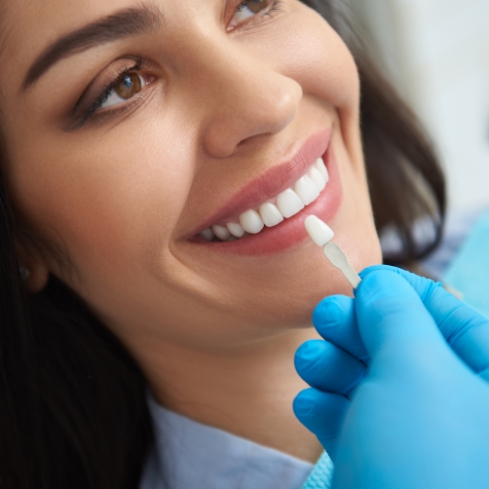 Older female patient looking at dentist holding fake tooth