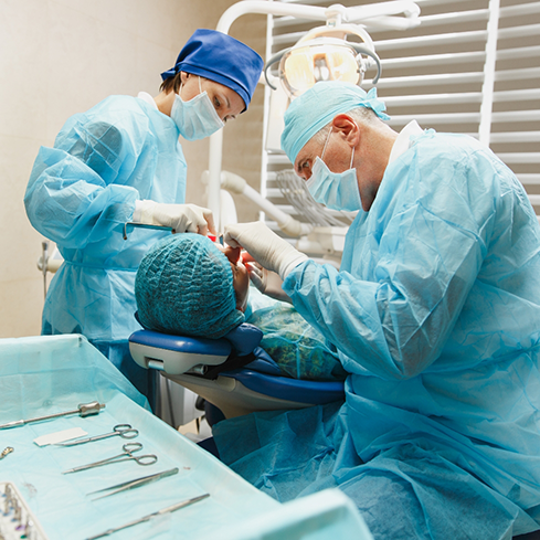 Dentist and assistant performing wisdom tooth extractions on a patient