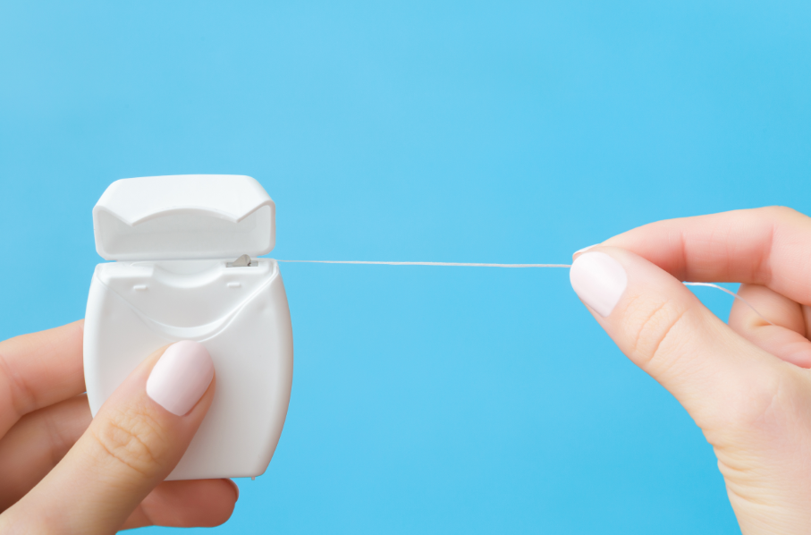 A hand pulling floss from a dispenser